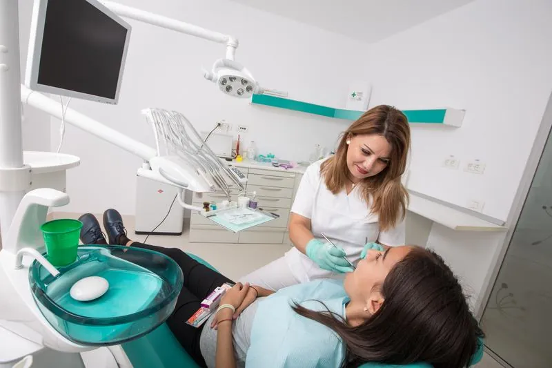 Medic stomatolog examinează o pacientă tânără în fotoliul dentar, la un control de rutină